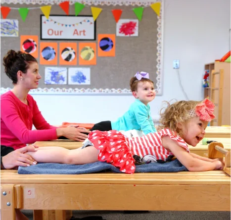 Young students working with staff in a Conductive Learning Center classroom.