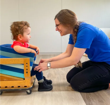 Educator helping a child use adaptive classroom equipment at Conductive Learning Center.