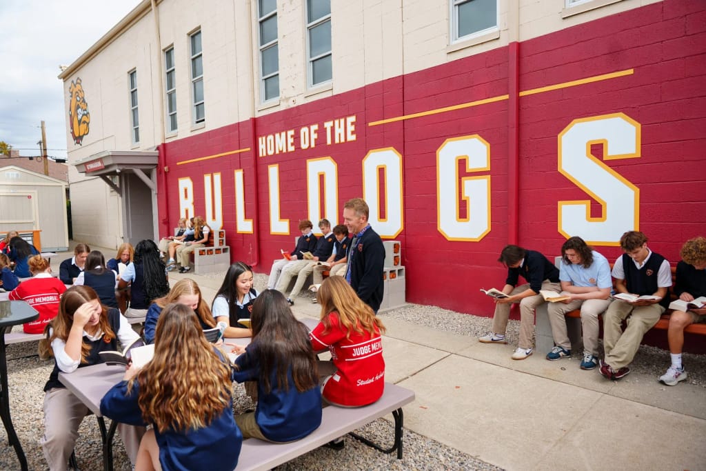 Judge Memorial Catholic High School students beside the campus Bulldog mural.