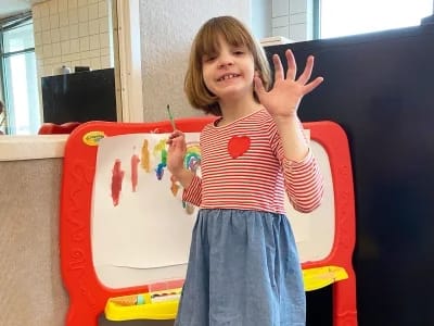 Carmen B. Pingree Autism Center student smiling beside a classroom easel.