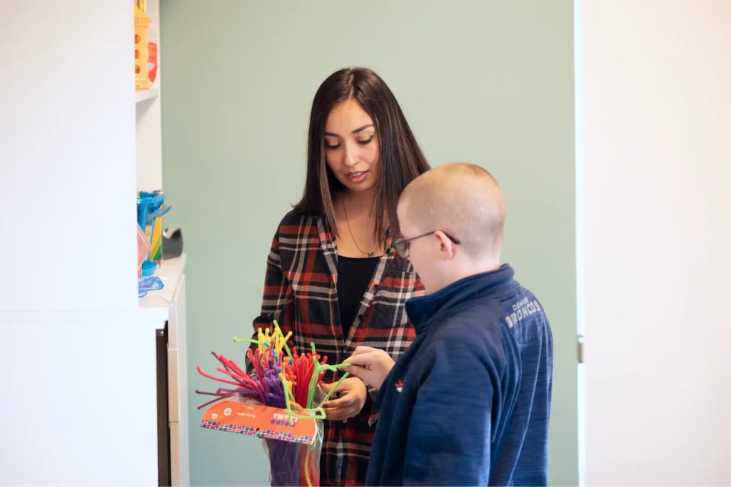 Adult and child working on a fine-motor activity at Woven Care Pueblo South