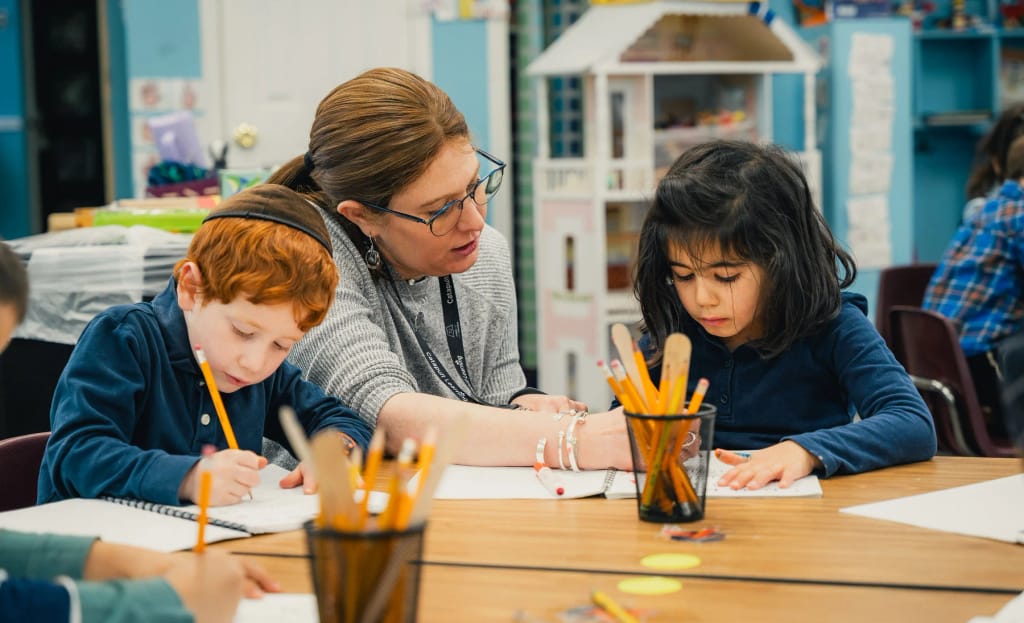 Teacher supporting two Keshet students with their schoolwork