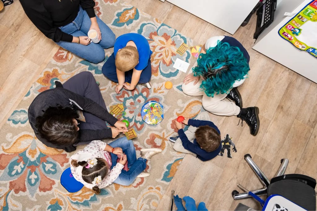 Children and adults gathered around toys at Woven Care Central West