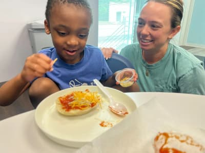 Abacus Therapies staff member supporting a child during an indoor mealtime activity.