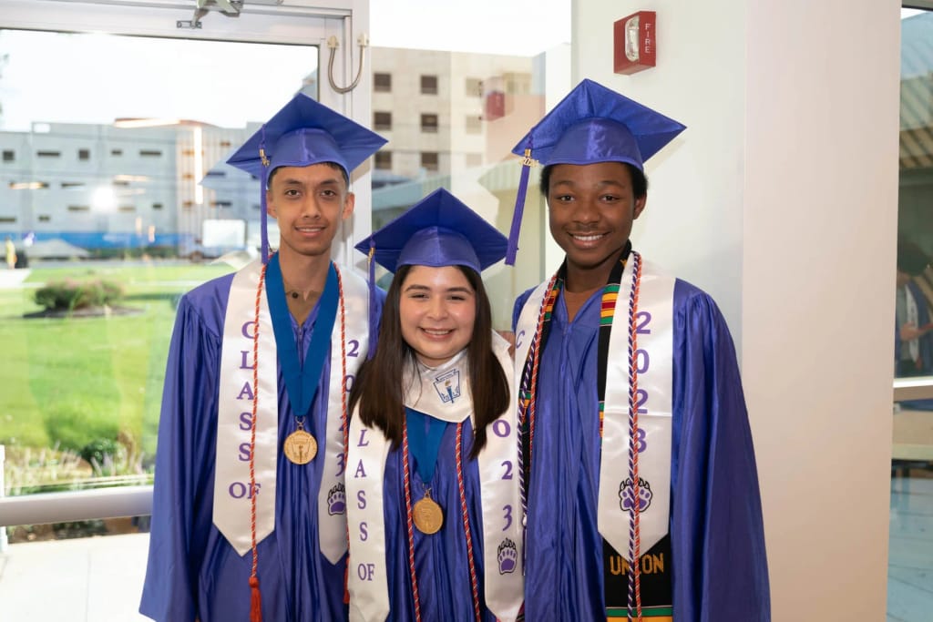 Austin Achieve graduates wearing caps and gowns inside the school building.