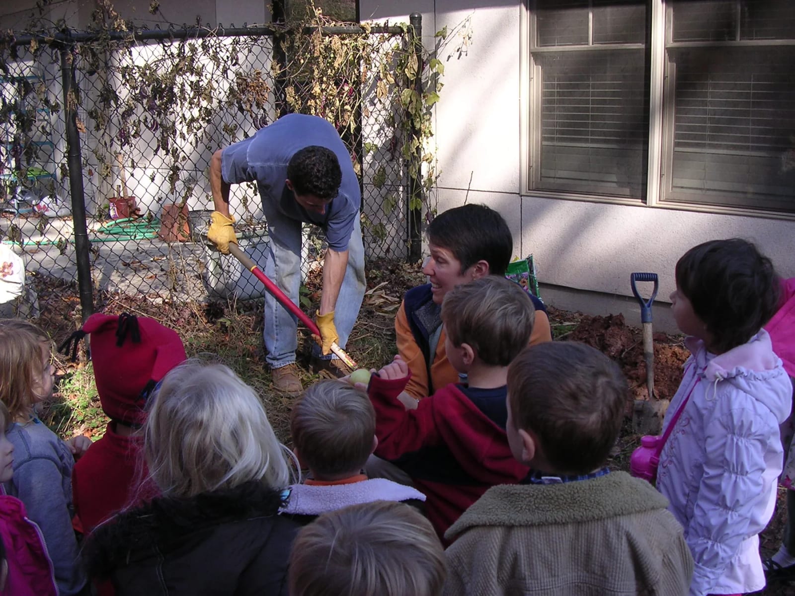 Asheville Montessori School students exploring soil with a teacher outdoors.
