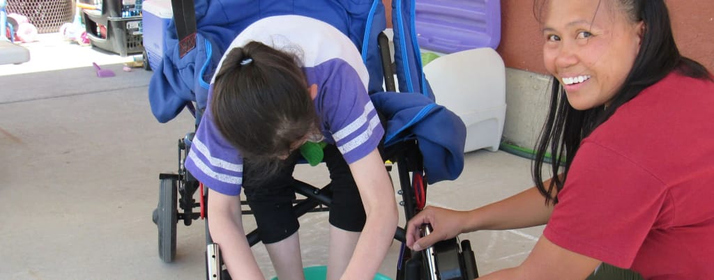 Adult supporting a child using mobility equipment