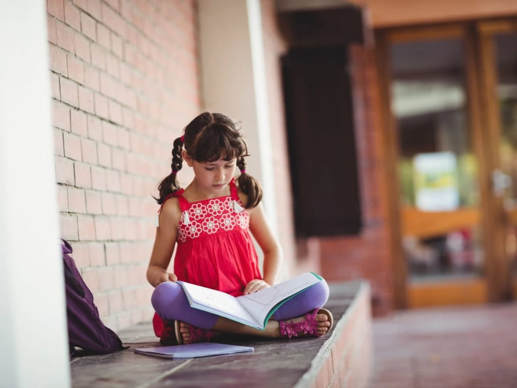 Student reading a book outside a school building