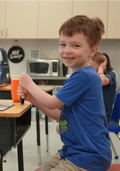 Smiling boy working at a classroom table at Emerald Coast Autism Center.