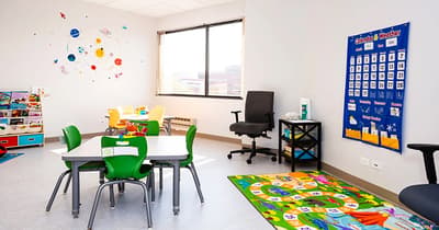 Therapy room at North Shore Pediatric Therapy with tables, chairs and play mat.