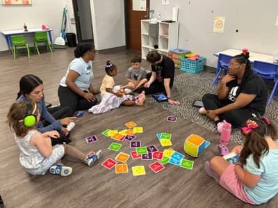 Children and therapists doing a group activity on a therapy room floor.