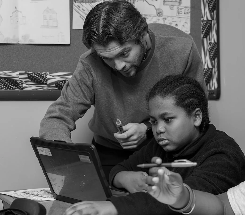 Pride Academy Charter School teacher guiding a student at a classroom table