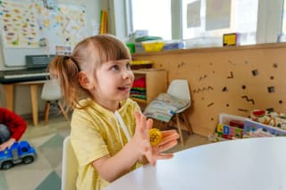 Child exploring a gold sensory ball in a classroom setting.