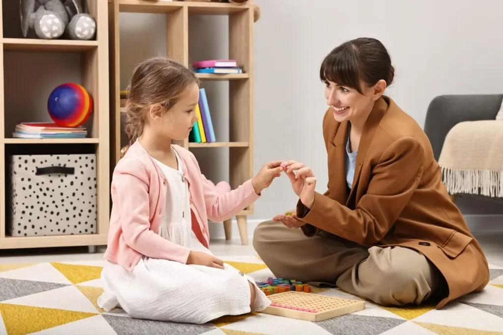 Therapist and child sitting on the floor during a play-based activity.
