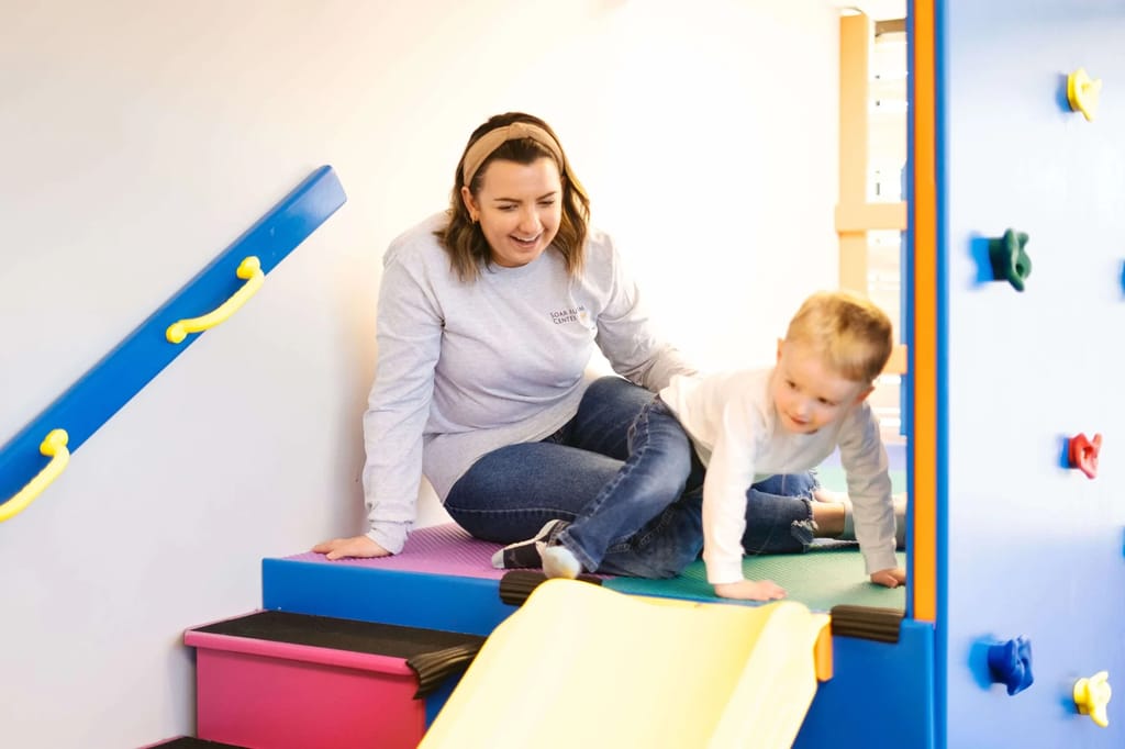 Adult supporting a young child on indoor climbing equipment