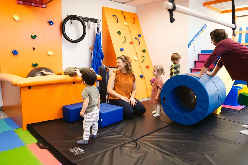 Children and adults using movement equipment in a therapy room