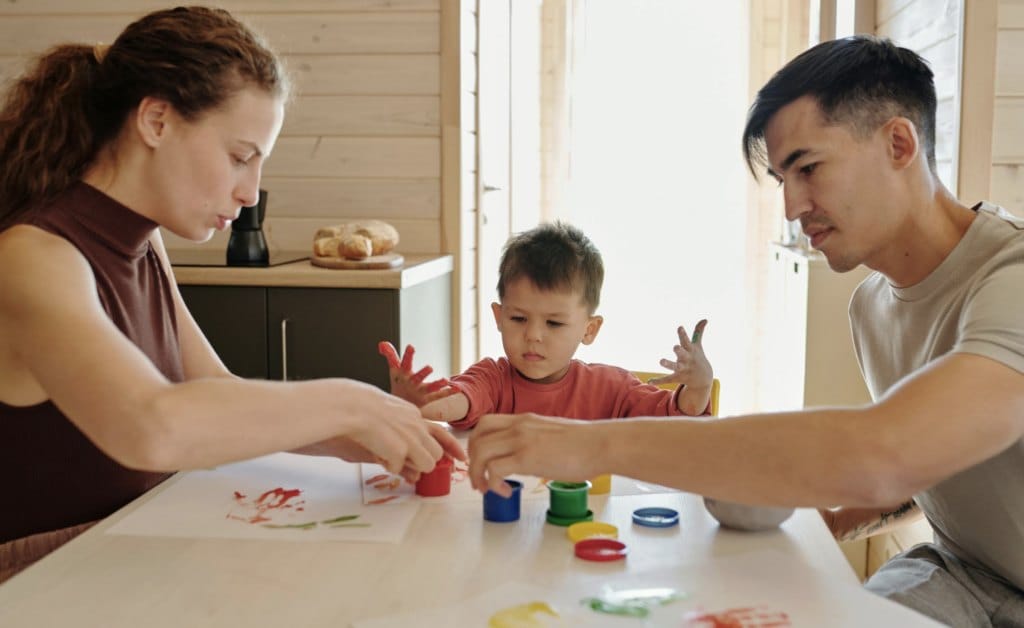 Parents and child painting together during an at-home activity
