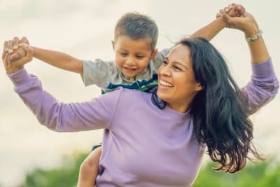 Adult carrying a smiling child outdoors