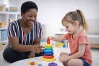 Therapist helping a young child with a stacking activity