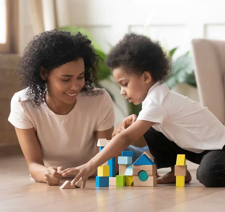 Adult helping a child build with colorful blocks