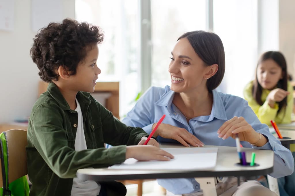 Teacher and student smiling together at a classroom table