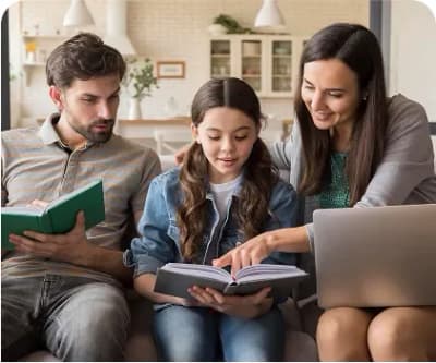 Family reading and using a tablet together on a sofa