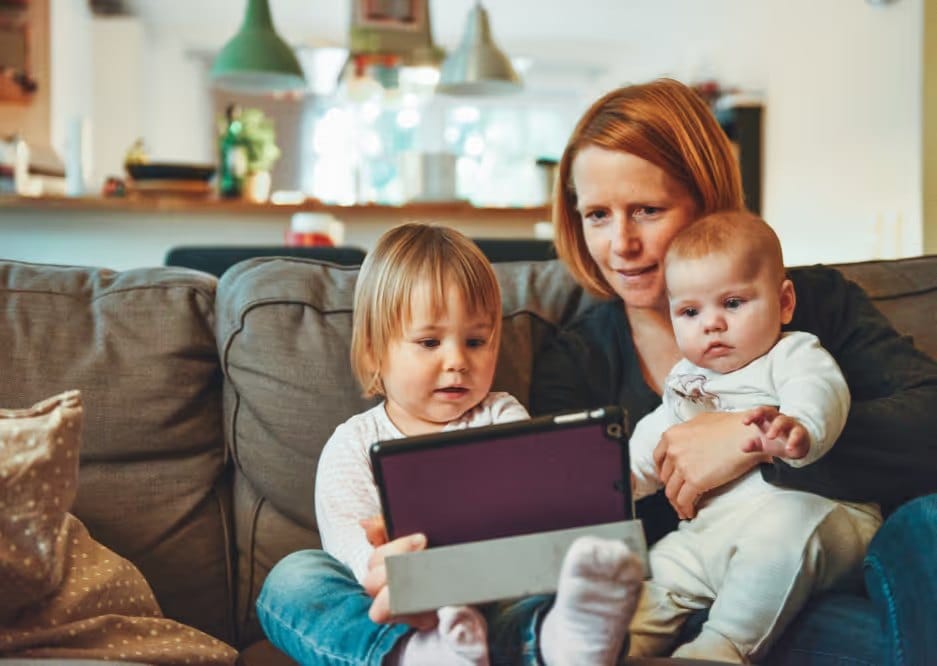 Parent and two young children using a tablet at home