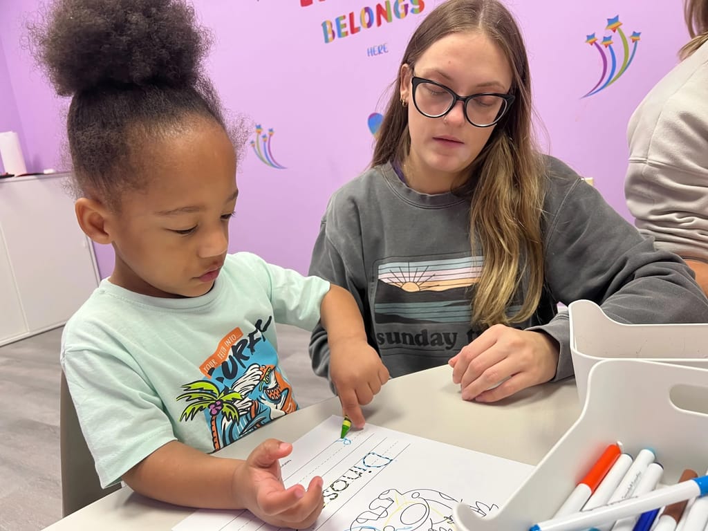 Child drawing under Registered Behavior Technician supervision