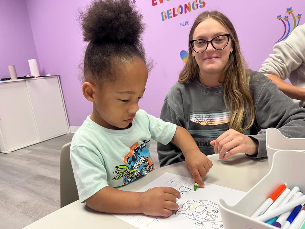 Child coloring and learning at desk with dedicated behavior technician