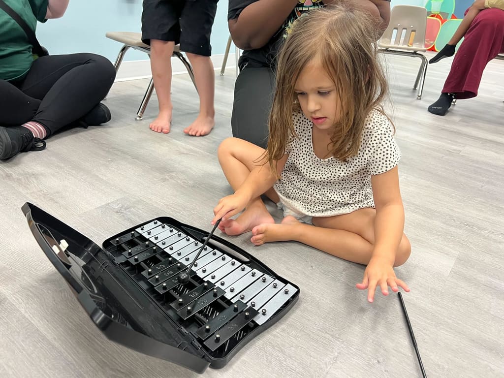 Child exploring music and rhythm playing a xylophone