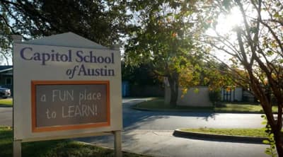 Capitol School of Austin sign beside the tree-lined entrance drive in Austin, Texas.