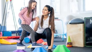 Therapist supporting a child during a balance activity