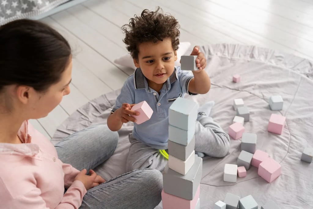 Caregiver and young child build a tower with soft blocks