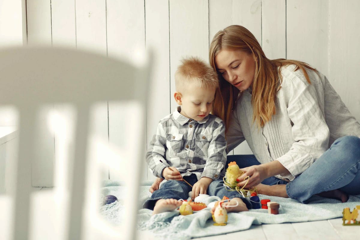 Adult supporting a young child during a play activity