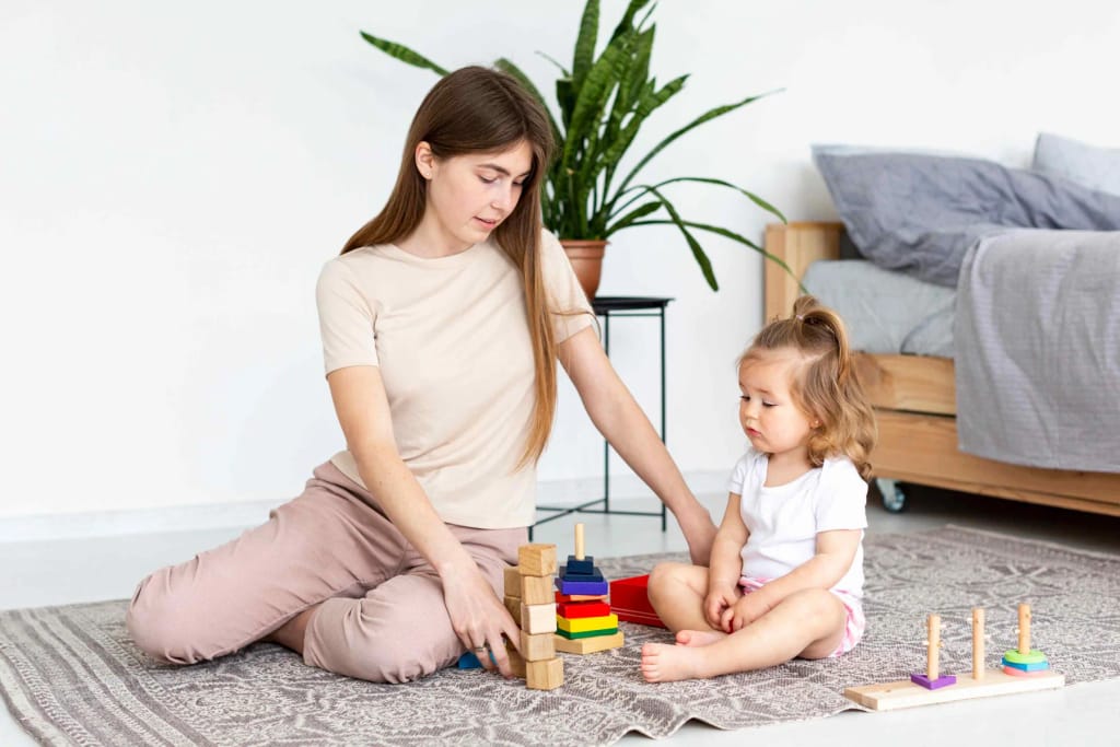 Adult helping a child stack colorful rings