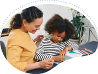 Adult supporting a child during a drawing activity