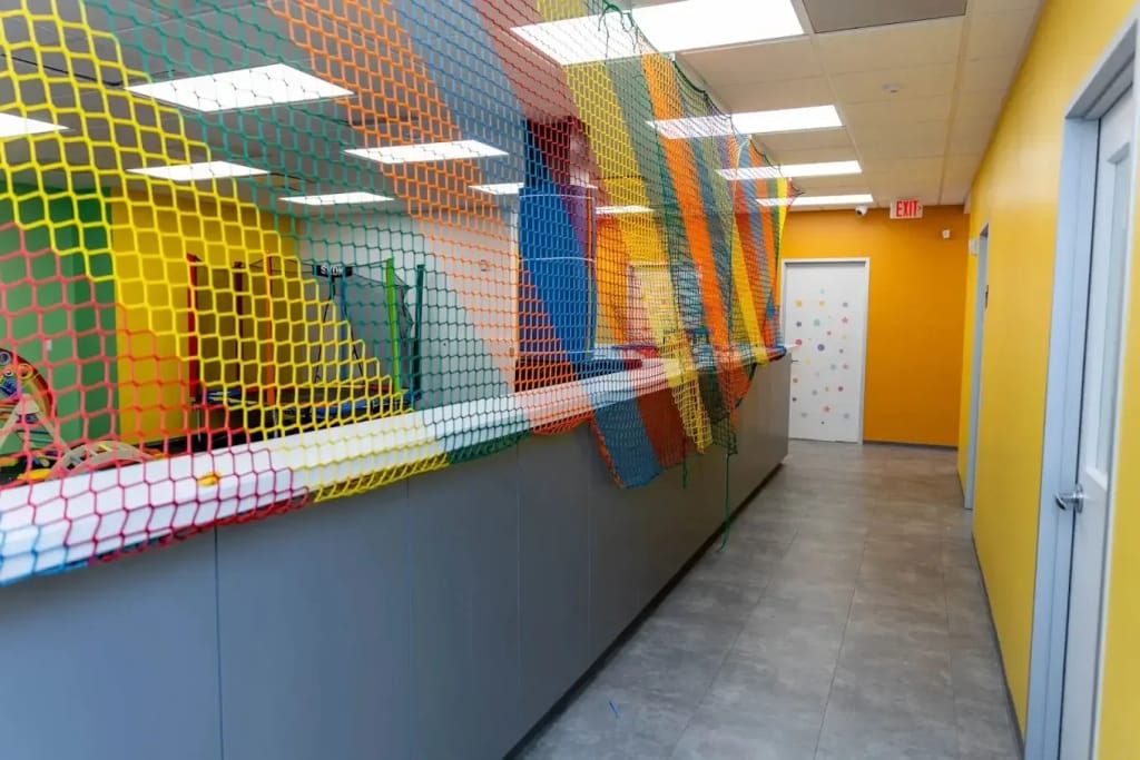 Colorful therapy corridor with a netted play area at Harmony ABA Centers