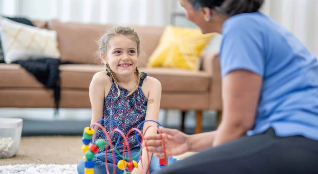 Child participating in a home-based learning activity with a therapist