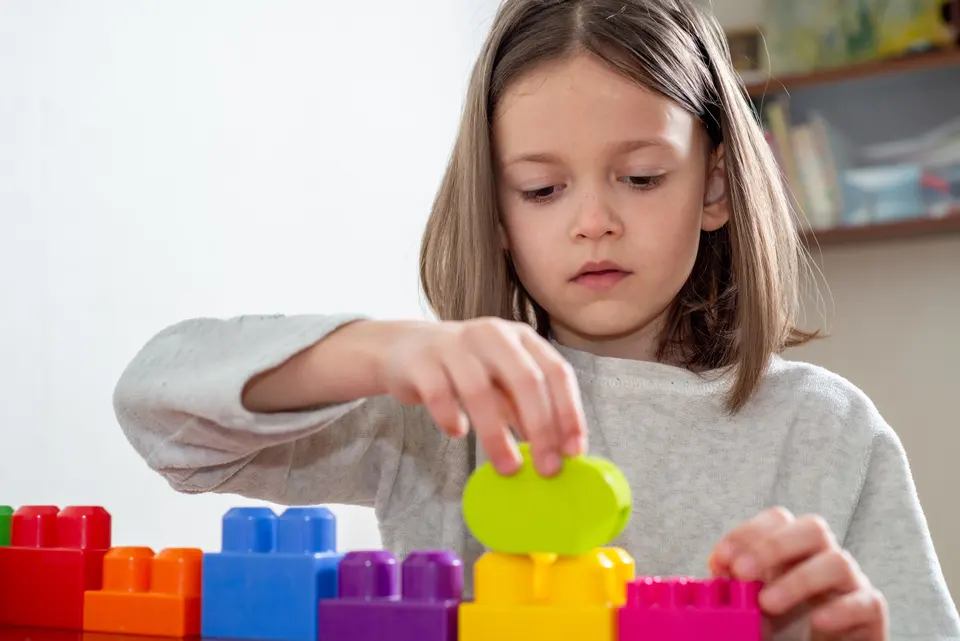 Child concentrating while building with colorful blocks